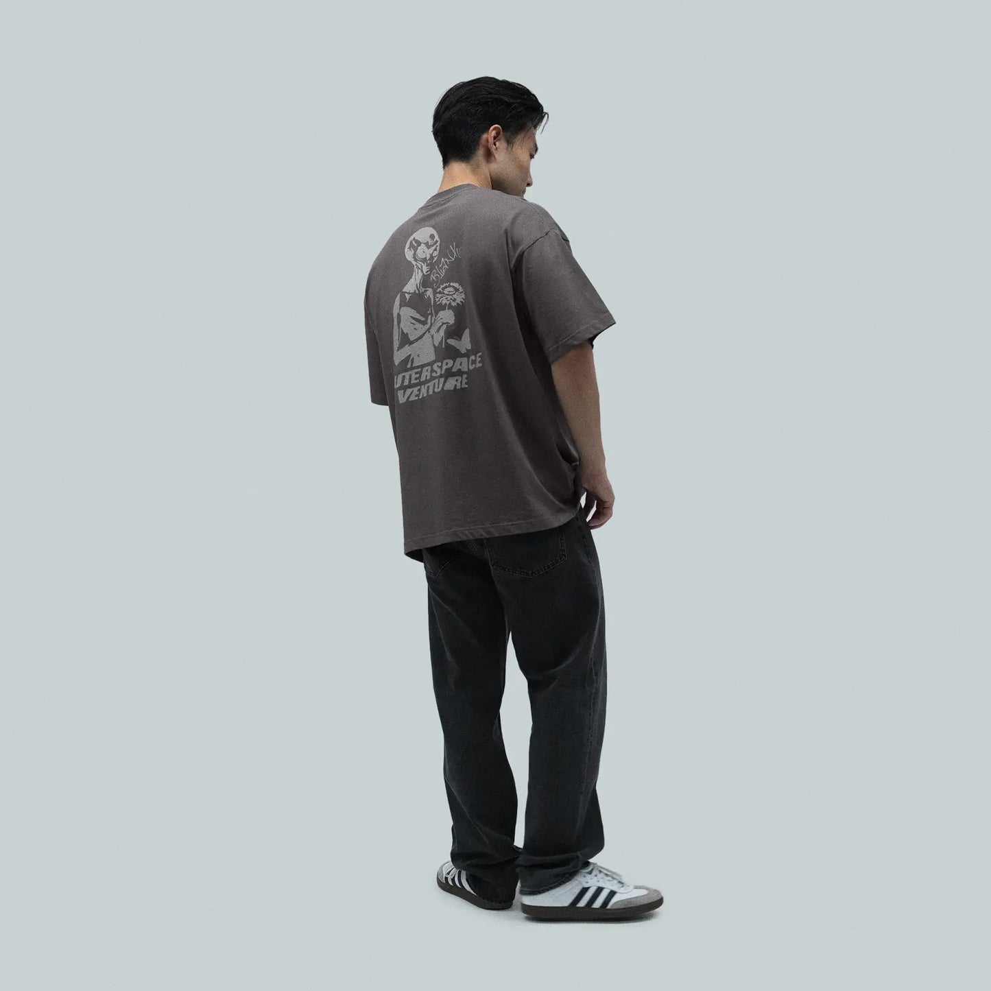 Model wearing Blank Project alien with flower and butterfly graphic short sleeve t-shirt in charcoal gray color